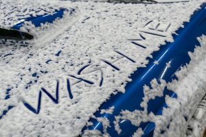 wash me written on car covered by foam